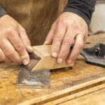 Wyprowadzanie krawędzi cykliny stolarskiej na kamieniu szlifierskim z użyciem drewnianego bloku prowadzącego