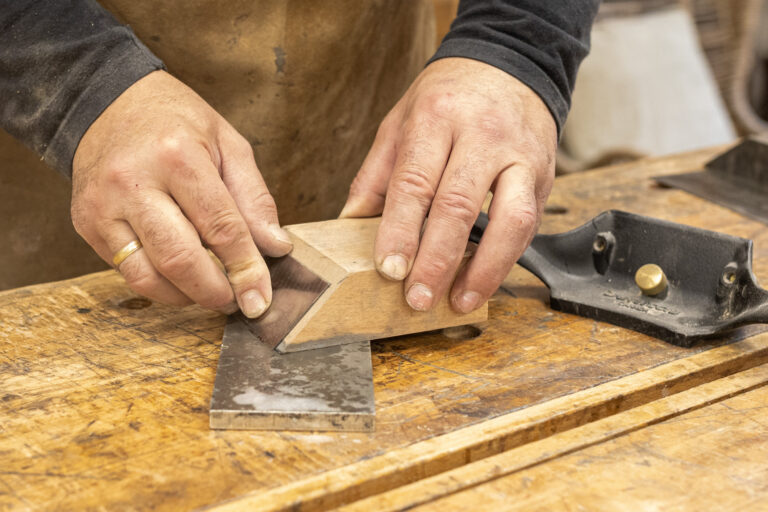 Wyprowadzanie krawędzi cykliny stolarskiej na kamieniu szlifierskim z użyciem drewnianego bloku prowadzącego