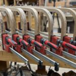 Ściski płaszczyznowe (równoległe) Bessey używane w warsztacie stolarskim podczas klejenia elementów drewnianych