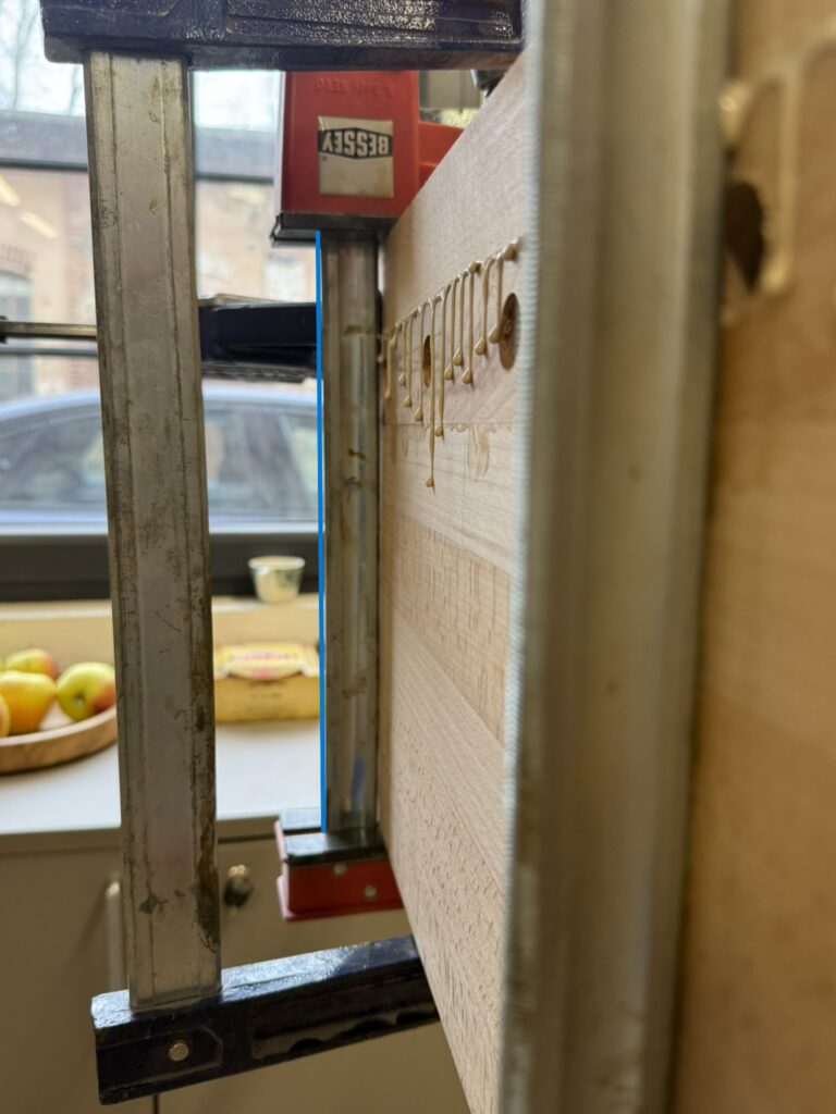 Bessey parallel-jaw clamp after heavy tightening showing jaw spreading and bar deflection marked with a straight line