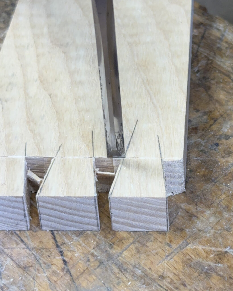 chisel placed between dovetail tails on the base line